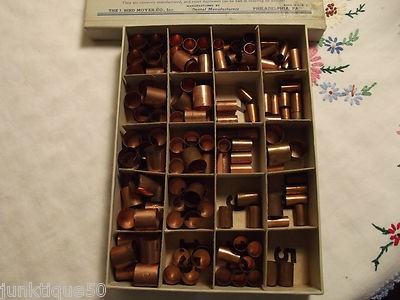 An old box filled with copper bands of assorted sizes for dental use.